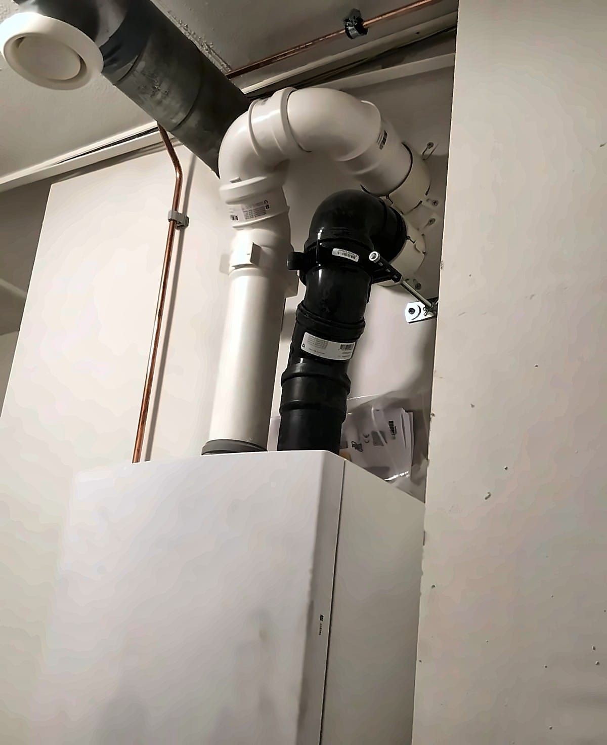 CV-ketel in een kast, met de buizen voor rookgasafvoer en luchttoevoer erboven