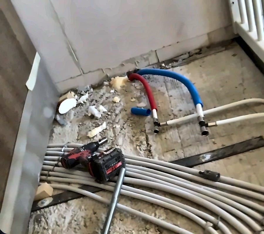 Rood en blauw geïsoleerde waterleidingen met persfittingen op een open vloer